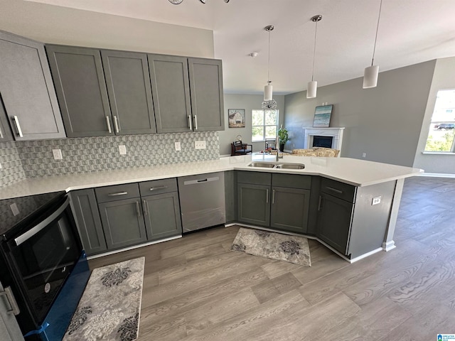 kitchen featuring light hardwood / wood-style floors, range with electric stovetop, kitchen peninsula, stainless steel dishwasher, and sink