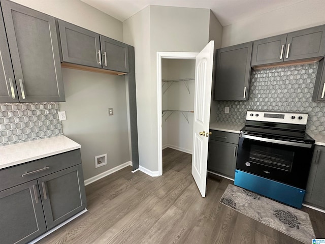 kitchen with wood-type flooring, stainless steel electric stove, backsplash, and gray cabinets