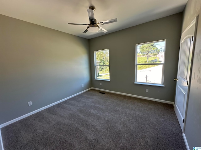 empty room with dark colored carpet and ceiling fan