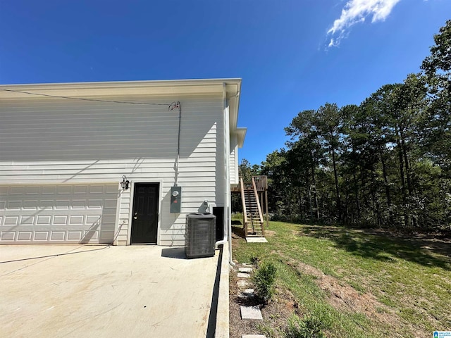 view of side of home featuring a garage, a lawn, and central AC