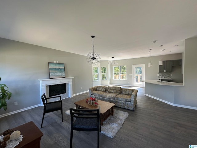 living room with a notable chandelier, sink, and dark hardwood / wood-style flooring