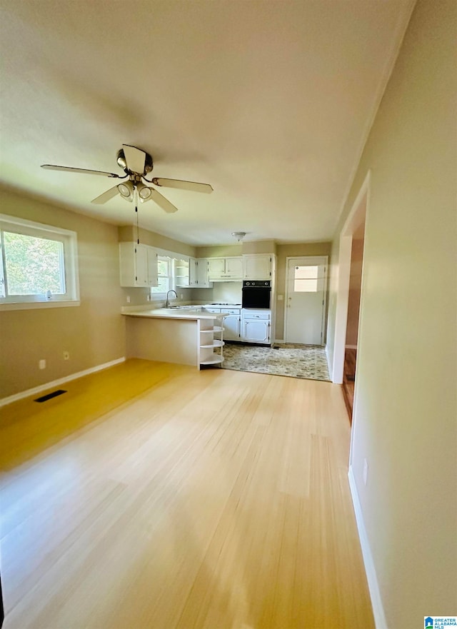 unfurnished living room with ceiling fan, light hardwood / wood-style flooring, and sink