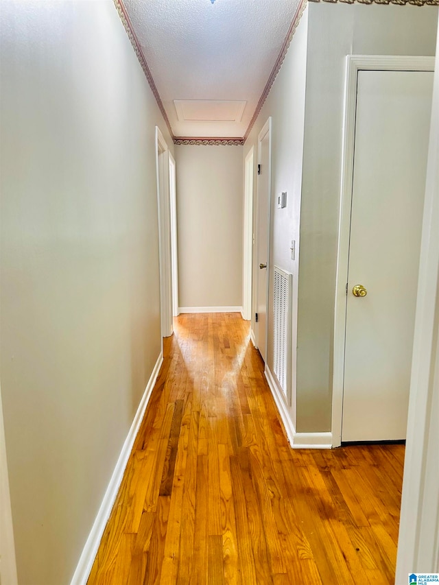 hallway with wood-type flooring, a textured ceiling, and crown molding