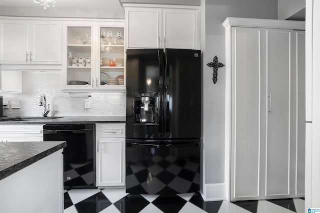 kitchen featuring sink, white cabinets, decorative backsplash, black appliances, and dark stone countertops