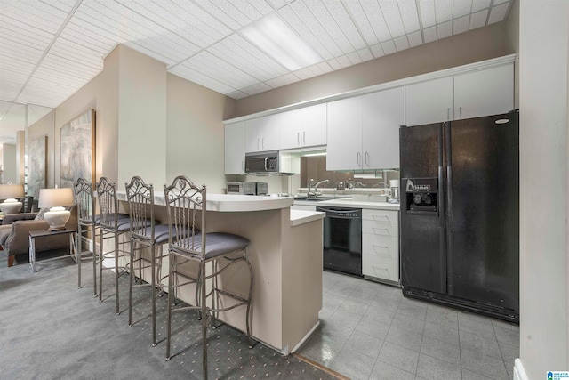 kitchen with a kitchen breakfast bar, white cabinets, kitchen peninsula, black appliances, and sink