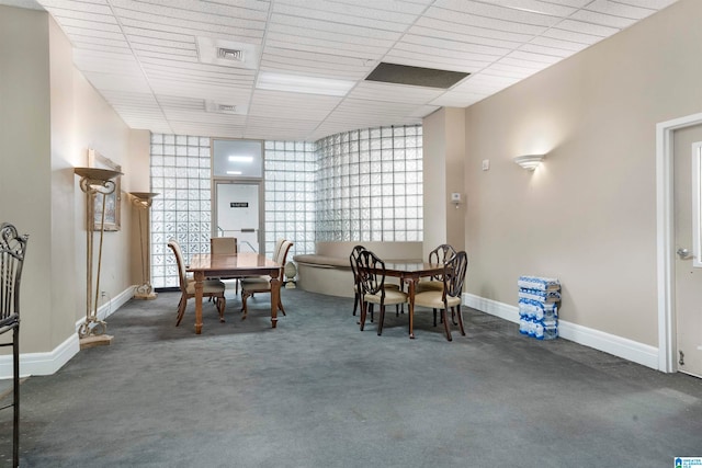 carpeted dining area with a drop ceiling