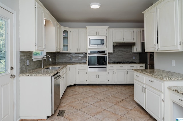 kitchen with light stone counters, sink, tasteful backsplash, white cabinetry, and stainless steel appliances