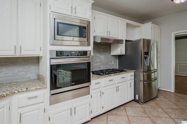 kitchen with stainless steel appliances, white cabinetry, light tile patterned flooring, and backsplash