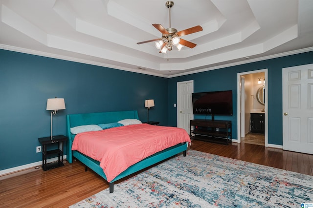 bedroom featuring ceiling fan, ensuite bathroom, a raised ceiling, and dark hardwood / wood-style flooring