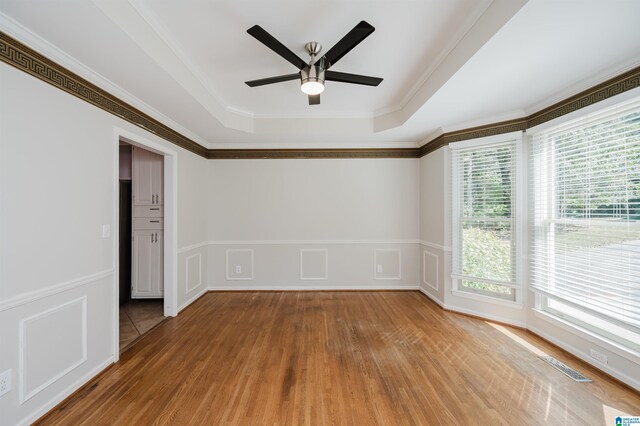 unfurnished room featuring hardwood / wood-style flooring, crown molding, ceiling fan, and a wealth of natural light