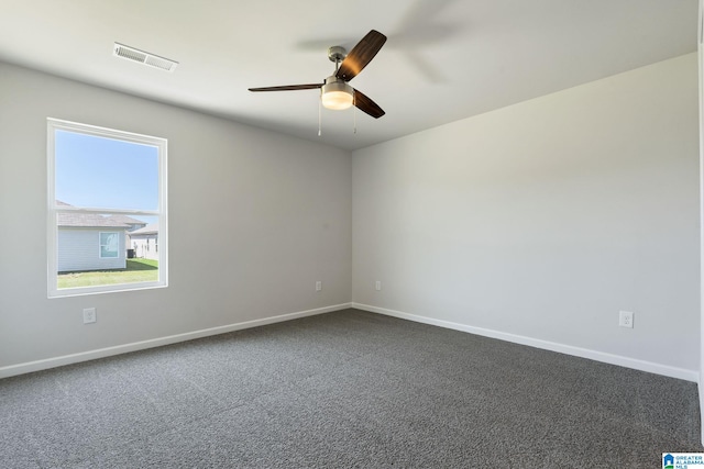 empty room featuring baseboards, visible vents, dark carpet, and a ceiling fan
