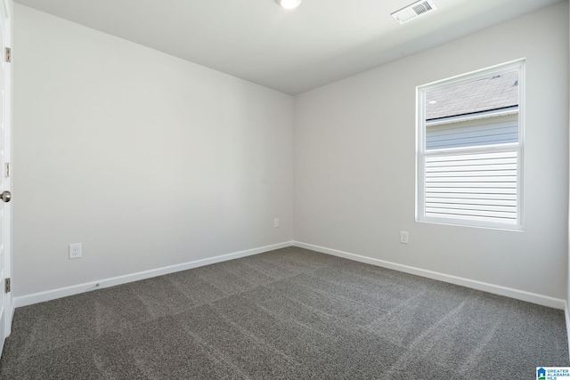 unfurnished room with baseboards, visible vents, and dark colored carpet