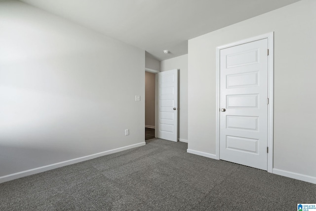 unfurnished bedroom with baseboards and dark carpet