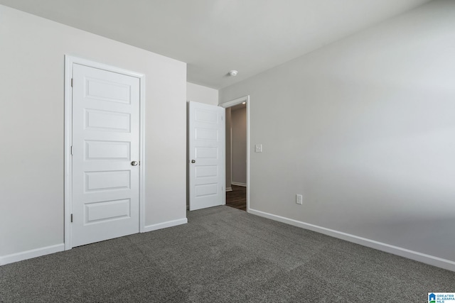 unfurnished bedroom with baseboards and dark carpet