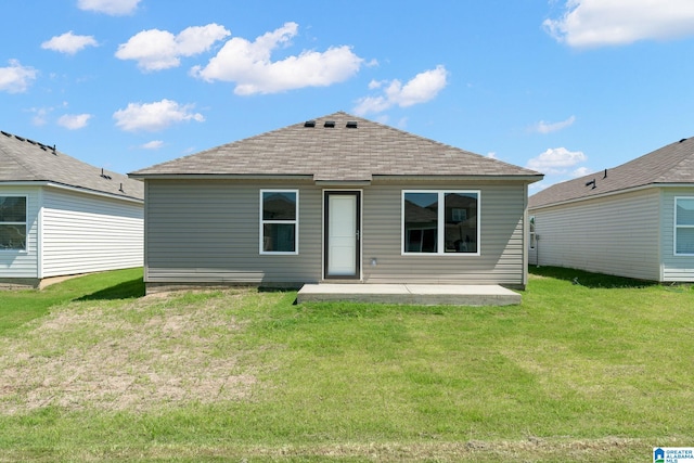rear view of house with roof with shingles, a patio, and a yard