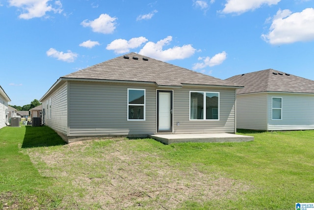 back of house with a patio, roof with shingles, and a lawn