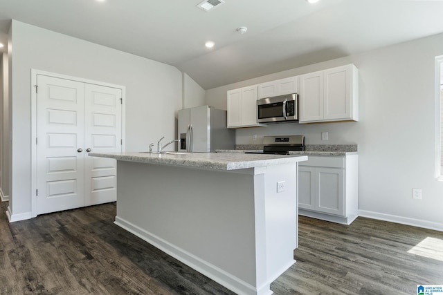 kitchen with vaulted ceiling, a sink, appliances with stainless steel finishes, a kitchen island with sink, and dark wood-type flooring