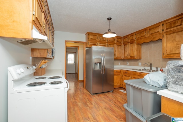 kitchen featuring hanging light fixtures, stainless steel fridge, sink, light hardwood / wood-style flooring, and electric range