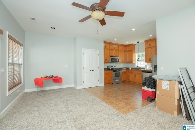 kitchen featuring appliances with stainless steel finishes, pendant lighting, ceiling fan, sink, and light carpet