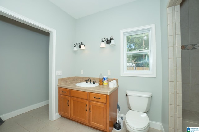 bathroom with vanity, tile patterned flooring, toilet, and tiled shower