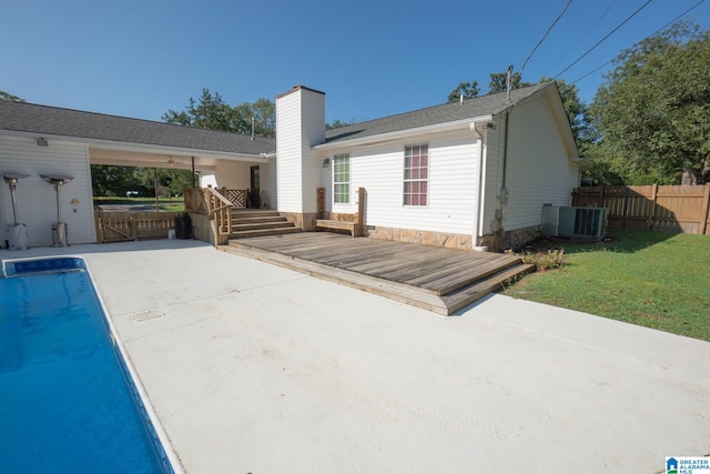 rear view of house featuring a pool side deck, a yard, central AC unit, and a patio area