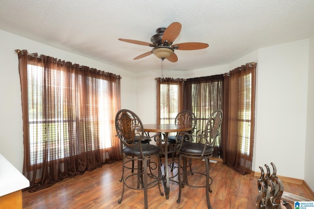 dining space featuring a textured ceiling, wood-type flooring, and ceiling fan