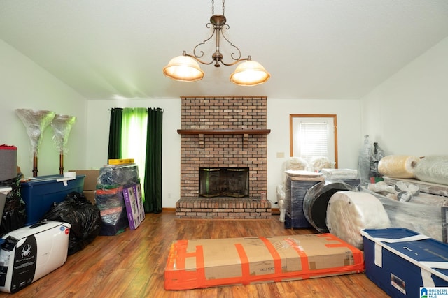 living room with a brick fireplace, a chandelier, and dark hardwood / wood-style flooring