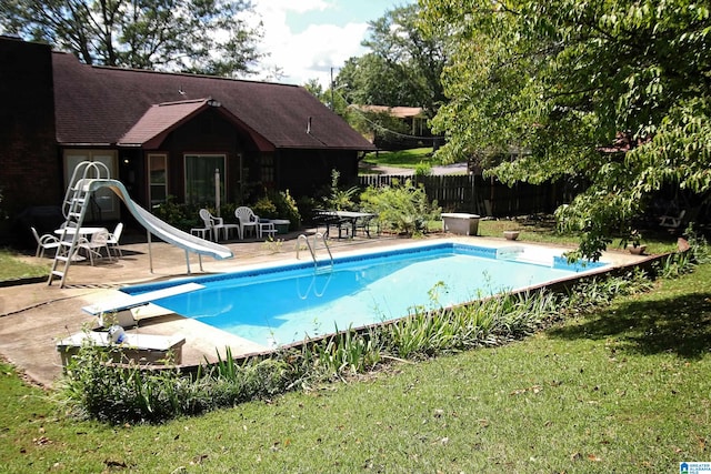 view of pool with a patio, a diving board, a yard, and a water slide