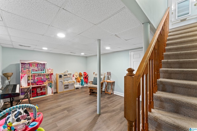 recreation room with wood-type flooring and a paneled ceiling