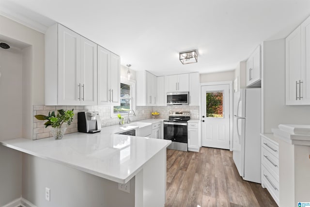 kitchen with stainless steel appliances, white cabinets, kitchen peninsula, and plenty of natural light