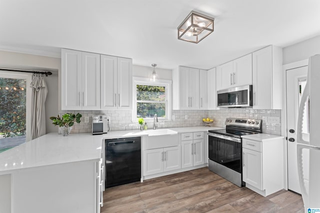 kitchen featuring sink, white cabinets, kitchen peninsula, light hardwood / wood-style flooring, and stainless steel appliances