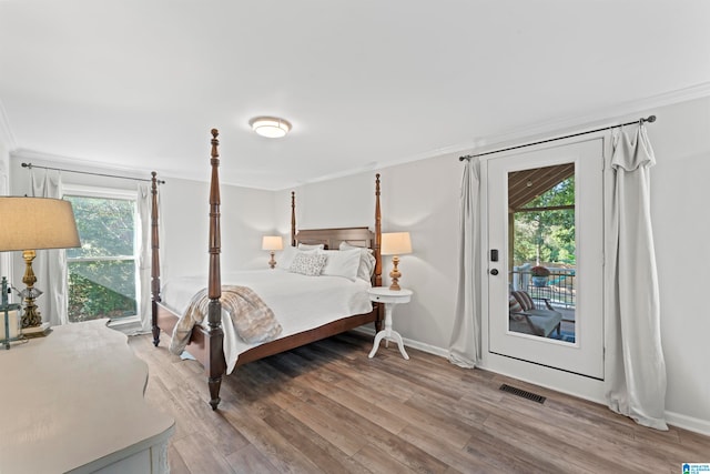 bedroom featuring ornamental molding, multiple windows, hardwood / wood-style flooring, and access to exterior