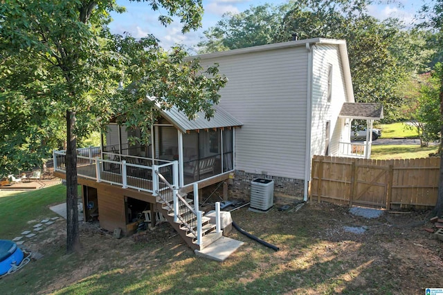 back of property with a yard, a sunroom, a wooden deck, and central air condition unit