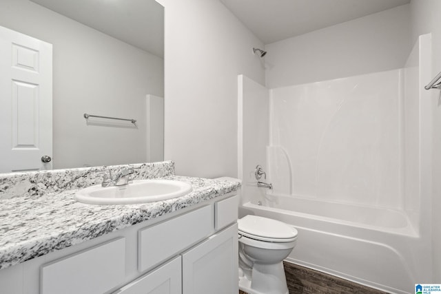 full bathroom featuring hardwood / wood-style flooring, bathing tub / shower combination, vanity, and toilet