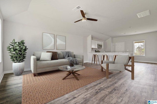 living room featuring wood-type flooring, vaulted ceiling, and ceiling fan