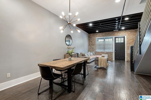 dining space with brick wall, dark hardwood / wood-style floors, and a chandelier