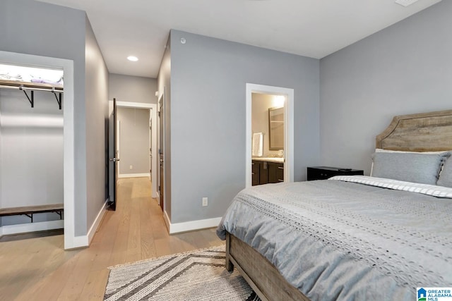 bedroom with ensuite bathroom, light hardwood / wood-style flooring, a closet, and a spacious closet