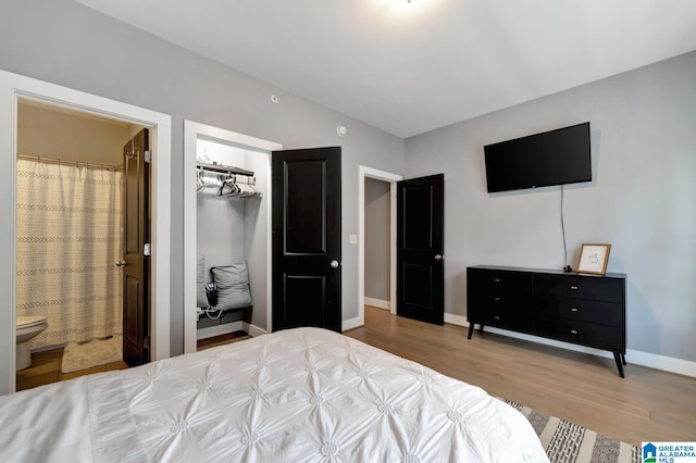 bedroom featuring light wood-type flooring, ensuite bathroom, and a closet