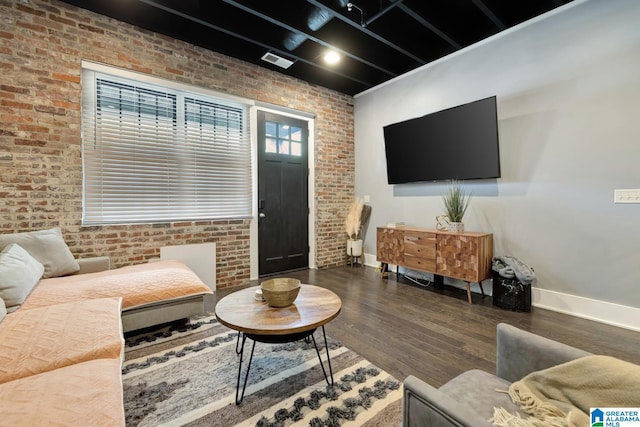 living room featuring brick wall and dark hardwood / wood-style flooring