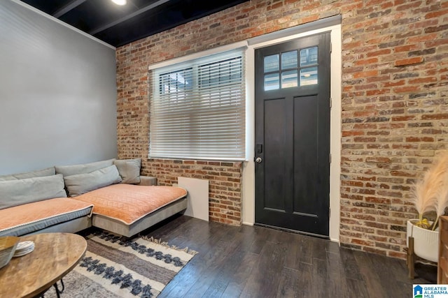 interior space with a wealth of natural light, brick wall, and dark hardwood / wood-style flooring