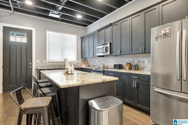 kitchen with stainless steel appliances, light hardwood / wood-style floors, a kitchen breakfast bar, and a kitchen island