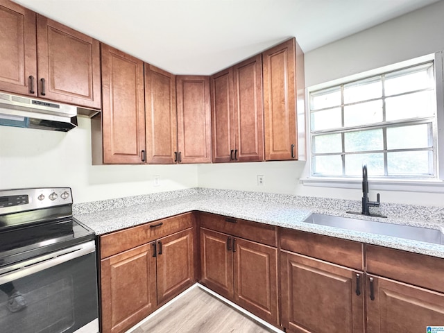 kitchen featuring stainless steel range with electric cooktop, light hardwood / wood-style floors, light stone countertops, and sink