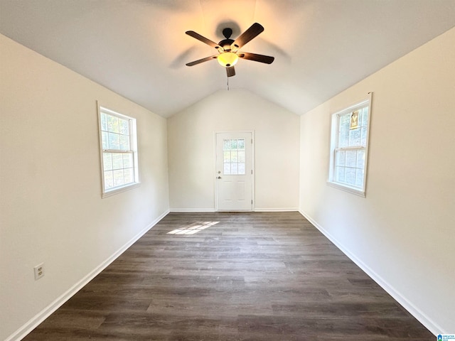 empty room featuring lofted ceiling, dark hardwood / wood-style floors, ceiling fan, and a wealth of natural light