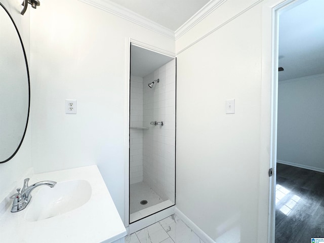 bathroom featuring hardwood / wood-style floors, vanity, crown molding, and a tile shower