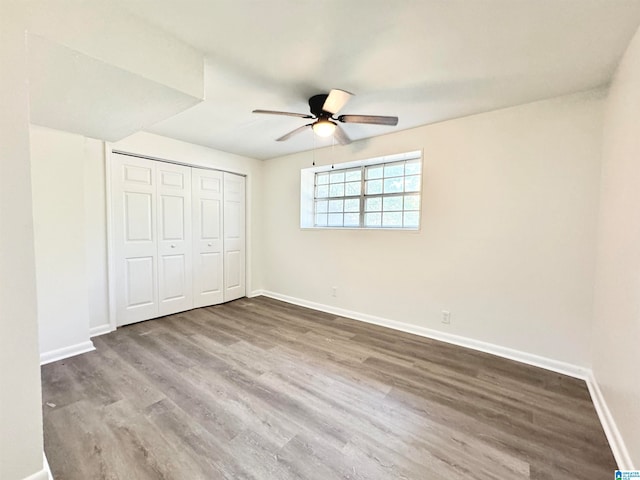 unfurnished bedroom with ceiling fan, a closet, and hardwood / wood-style flooring