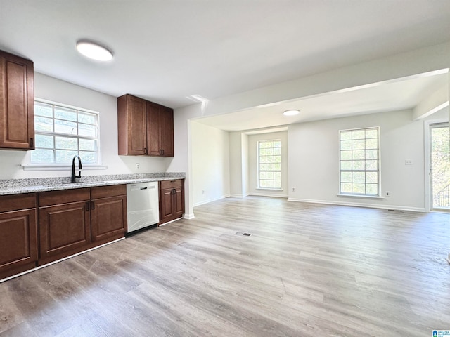 kitchen with dark brown cabinets, sink, light hardwood / wood-style flooring, light stone countertops, and stainless steel dishwasher