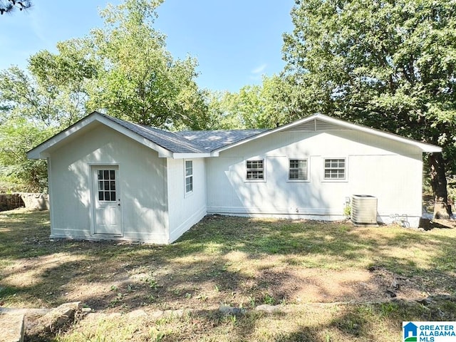 rear view of property featuring a lawn and central AC unit