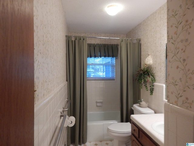 full bathroom with a textured ceiling, tile walls, vanity, and toilet