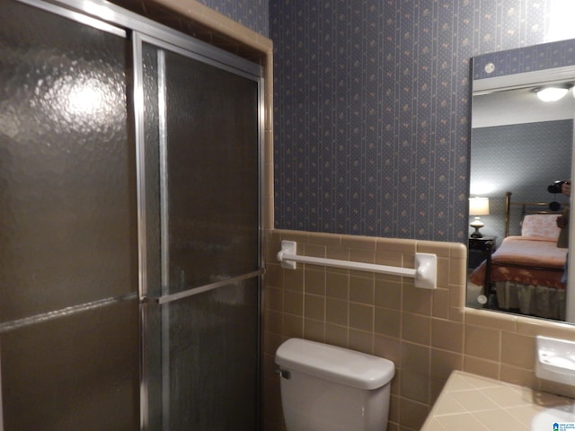 bathroom with tile walls, toilet, and an enclosed shower