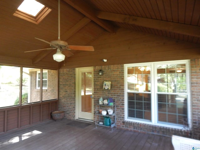 unfurnished sunroom featuring wooden ceiling, vaulted ceiling with skylight, and ceiling fan